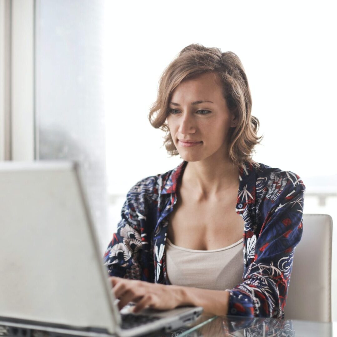 A woman sitting at a table with her laptop.